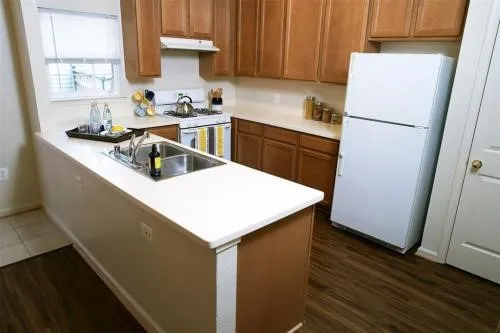 a kitchen with a sink a refrigerator a window and cabinets