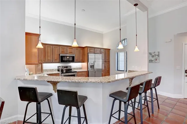 a kitchen with stainless steel appliances kitchen island granite countertop a dining table chairs and a refrigerator