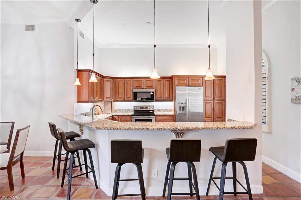 6535 Valen Way, Unit E202 Naples, FL 34108 - Photo 15 of 33 a kitchen with stainless steel appliances granite countertop a table chairs and a refrigerator