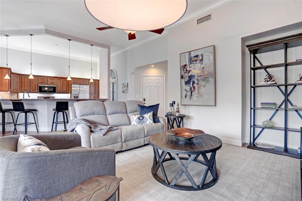 6535 Valen Way, Unit E202 Naples, FL 34108 - Photo 6 of 33 a living room with furniture a table and kitchen view