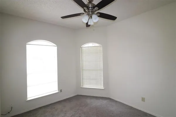 an empty room with a window and a fan