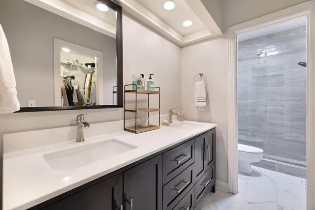 a bathroom with a double vanity sink toilet and mirror