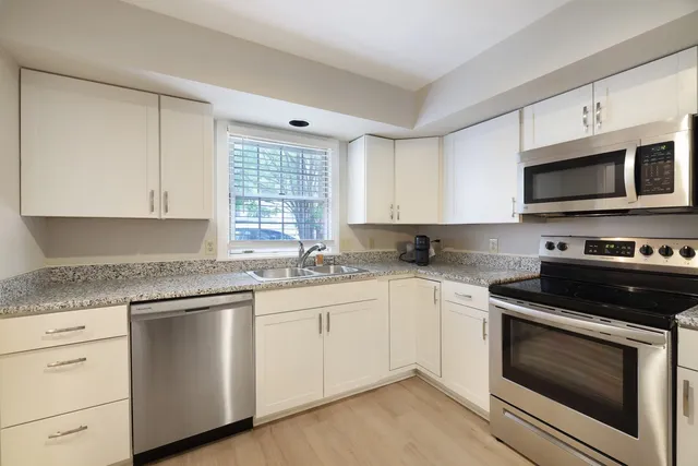 a kitchen with granite countertop white cabinets and appliances