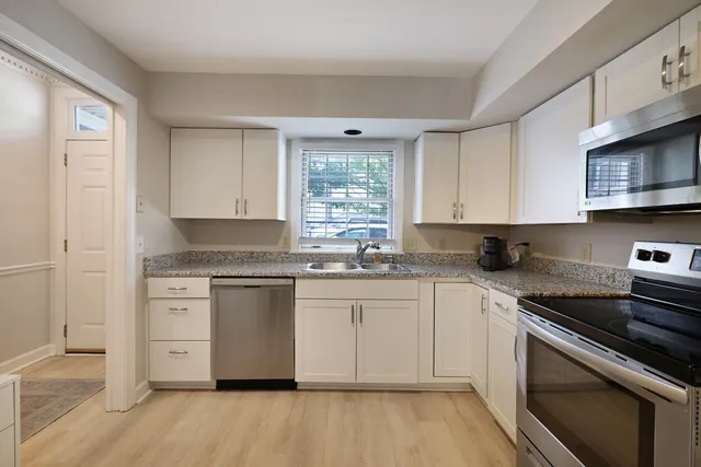 a kitchen with stainless steel appliances granite countertop a stove and white cabinets