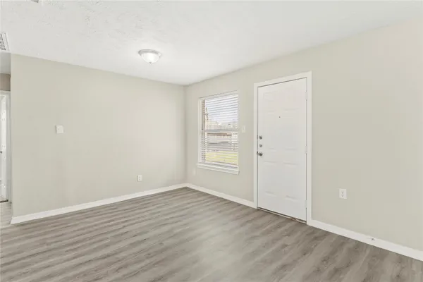a view of an empty room with wooden floor and a window