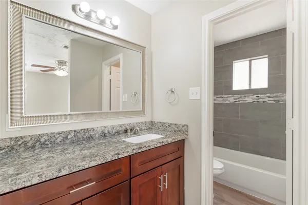 a bathroom with a granite countertop sink a mirror and a bathtub