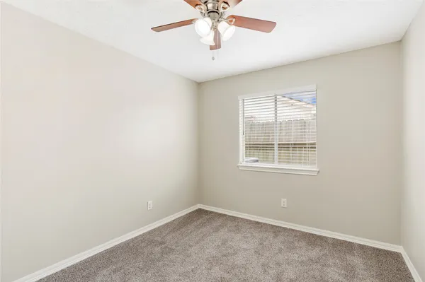 an empty room with a window and a ceiling fan