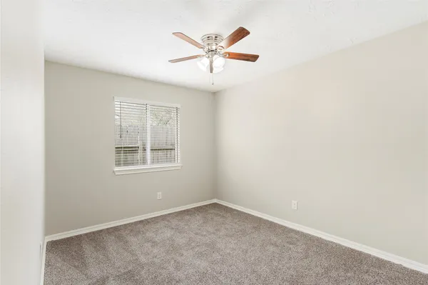 an empty room with a ceiling fan and window