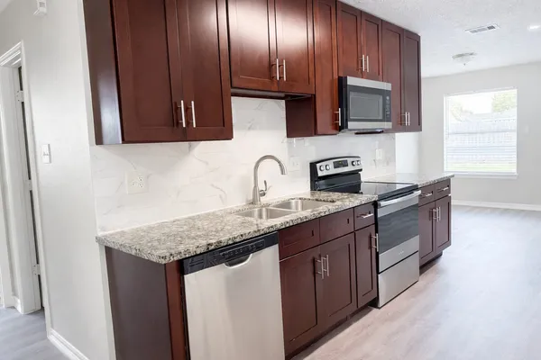 a kitchen with stainless steel appliances granite countertop a sink stove and cabinets