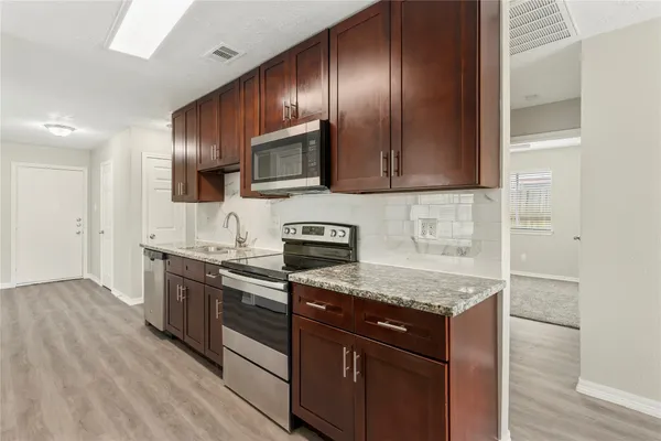 a kitchen with granite countertop wooden cabinets stainless steel appliances and a counter space