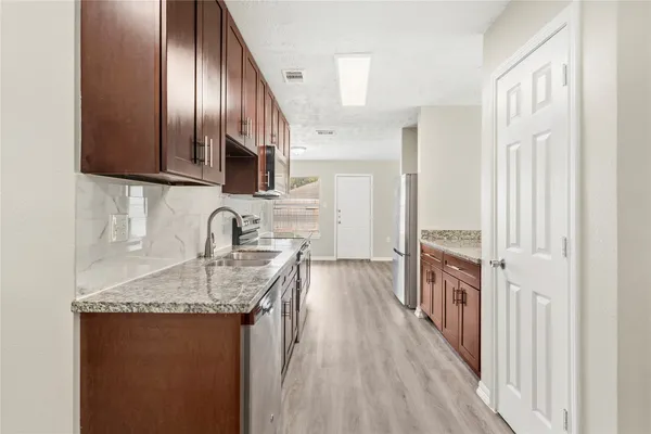 a kitchen with granite countertop a sink stove and refrigerator