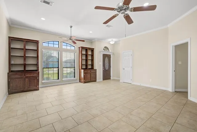 a view of an empty room with a window and kitchen view