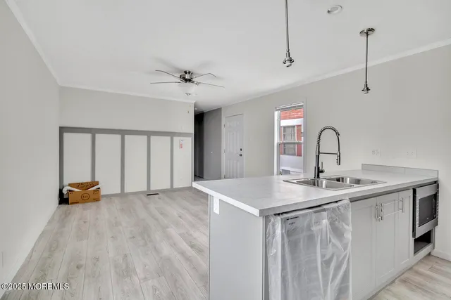 a kitchen with a sink a chandelier and wooden floor