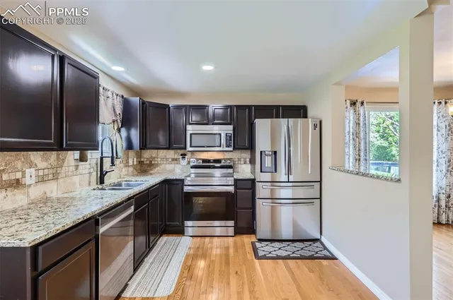 a kitchen with stainless steel appliances granite countertop a refrigerator and a stove top oven