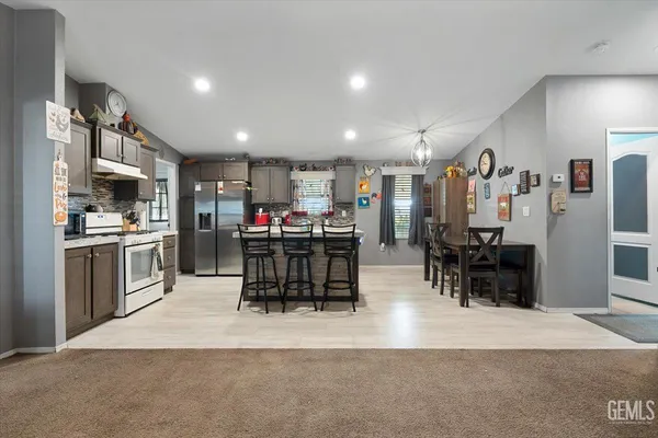 a kitchen with stainless steel appliances kitchen island granite countertop a refrigerator a oven a sink a dining table and chairs