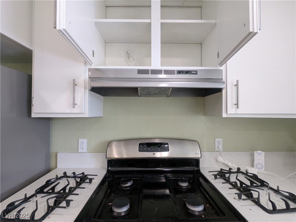 7301 Pleasant View Avenue Las Vegas, NV 89147 - Photo 12 of 37 Kitchen featuring stainless steel range with gas cooktop, white cabinetry, under cabinet range hood, and light countertops