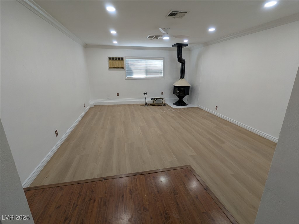 7301 Pleasant View Avenue Las Vegas, NV 89147 - Photo 7 of 37 Unfurnished living room with a wood stove, light wood-style flooring, ornamental molding, and recessed lighting