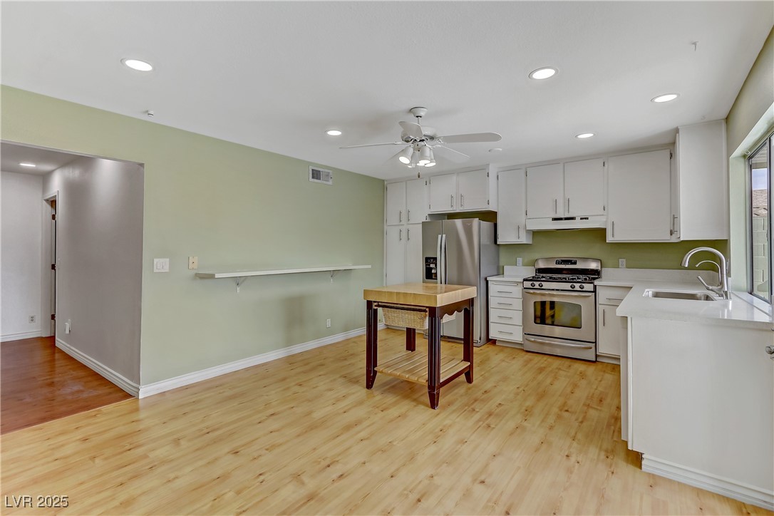 7301 Pleasant View Avenue Las Vegas, NV 89147 - Photo 10 of 37 Kitchen featuring recessed lighting, stainless steel appliances, light wood finished floors, a ceiling fan, and white cabinets