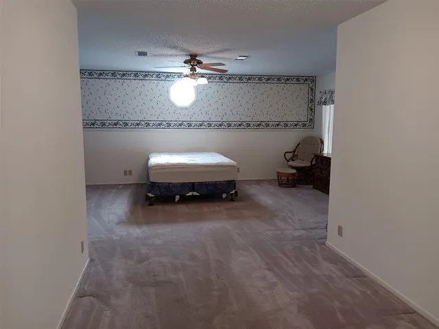 a bed sitting in a spacious bedroom next to a window