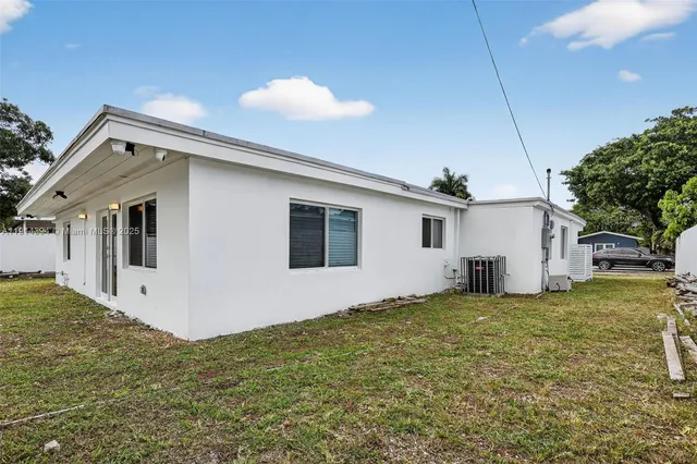 a view of a white house next to a yard with a big yard