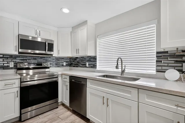 a kitchen with granite countertop a sink stainless steel appliances and cabinets