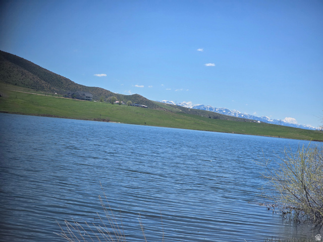 8400 North Treasurton Road Preston, ID 83263 - Photo 13 of 13 Tranquil waterfront setting featuring a body of water, green hillsides, distant snow-capped mountains, and a clear blue sky