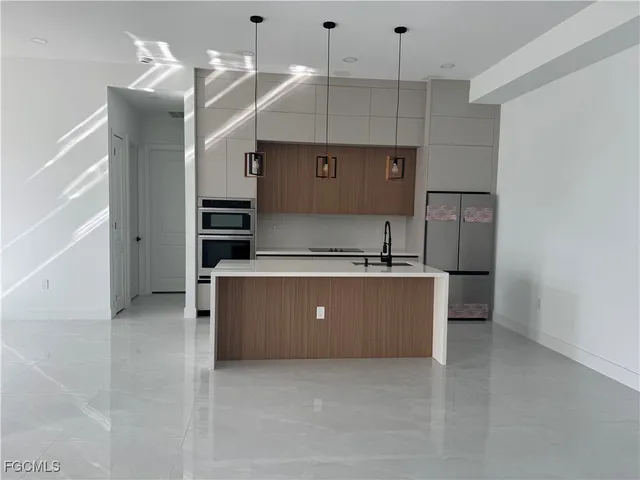 a kitchen with kitchen island a counter top space a sink stainless steel appliances and cabinets