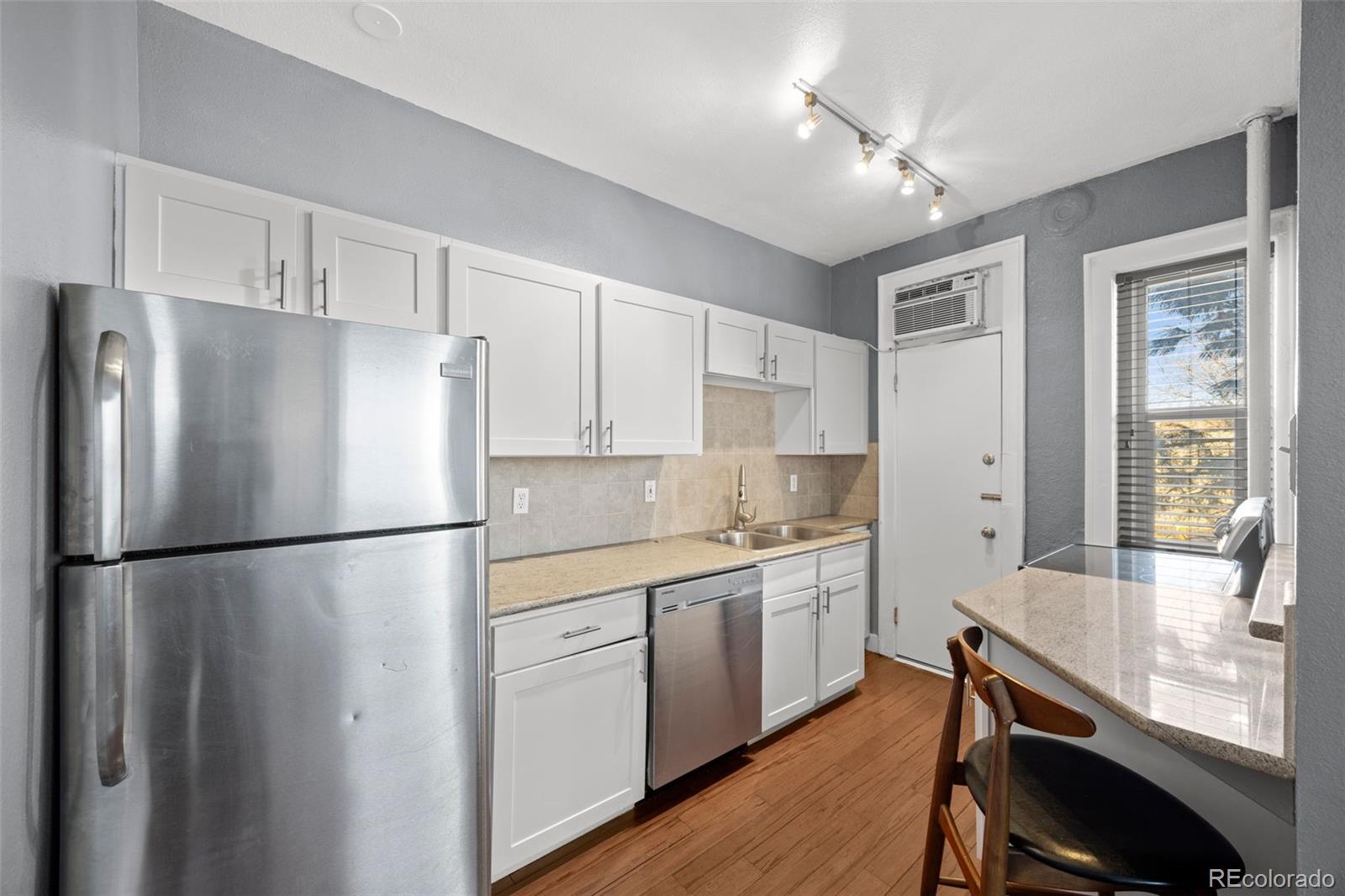 1376 Pearl Street, Unit 211 Denver, CO 80203 - Photo 17 of 26 a kitchen with a refrigerator a sink dishwasher and white cabinets with wooden floor