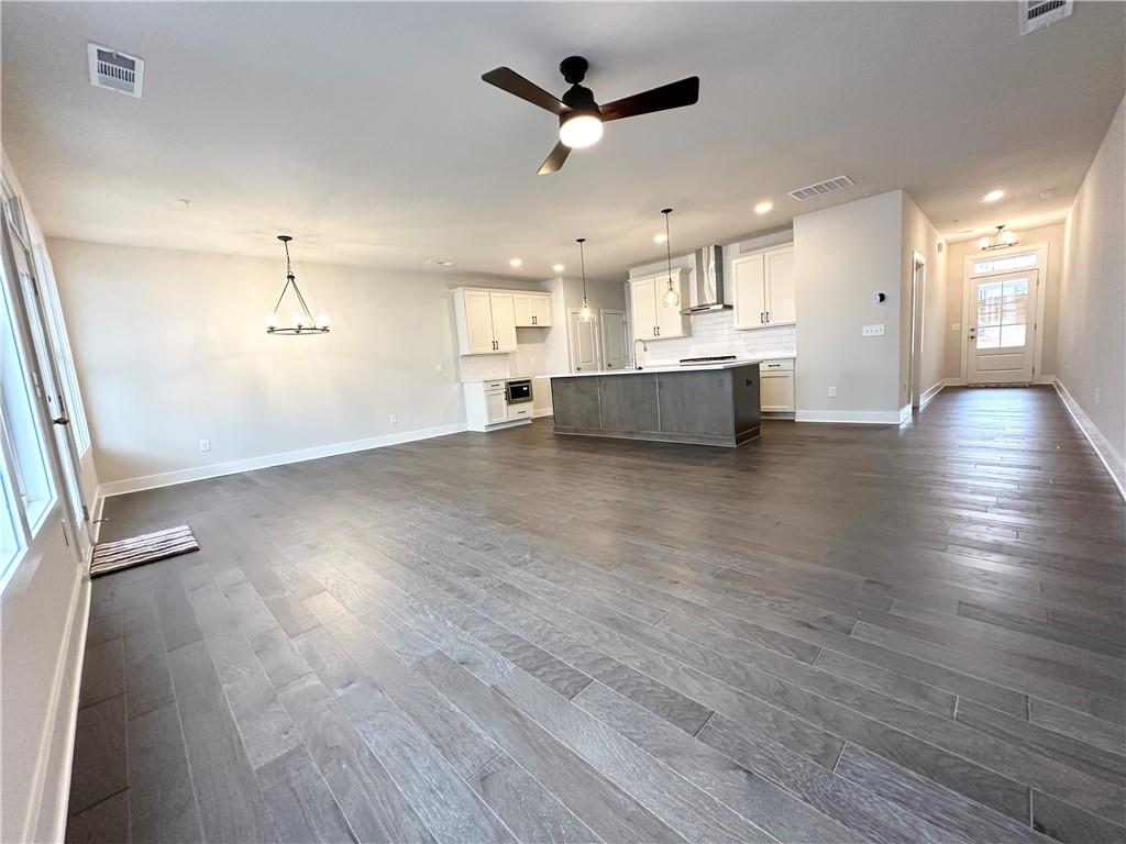 1237 Waldon Crossing Cumming, GA 30041 - Photo 2 of 29 an empty room with wooden floor a ceiling fan and kitchen view