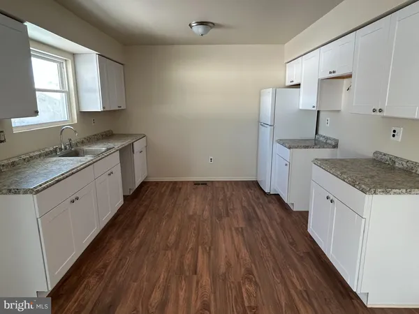 a kitchen with a hard wood floor white cabinets and sink