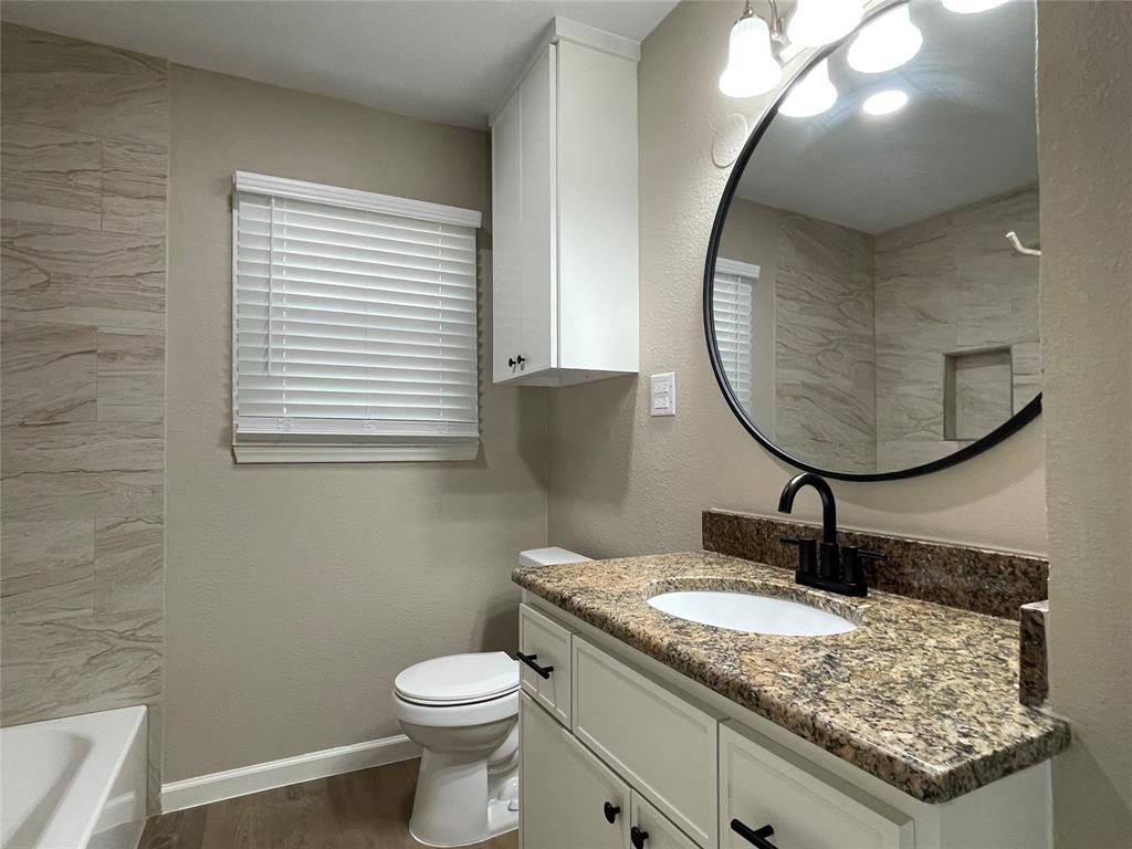 2203 Fowler Drive Denton, TX 76209 - Photo 11 of 18 a bathroom with a granite countertop toilet a sink and a mirror