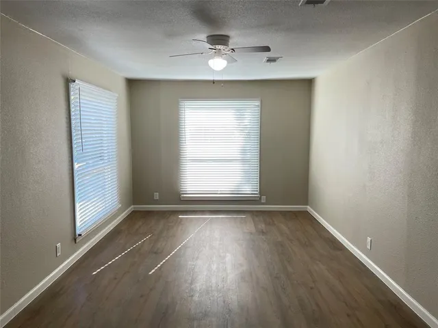 an empty room with wooden floor windows and entrance
