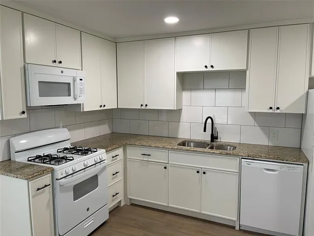 a kitchen with granite countertop white cabinets white stainless steel appliances and sink