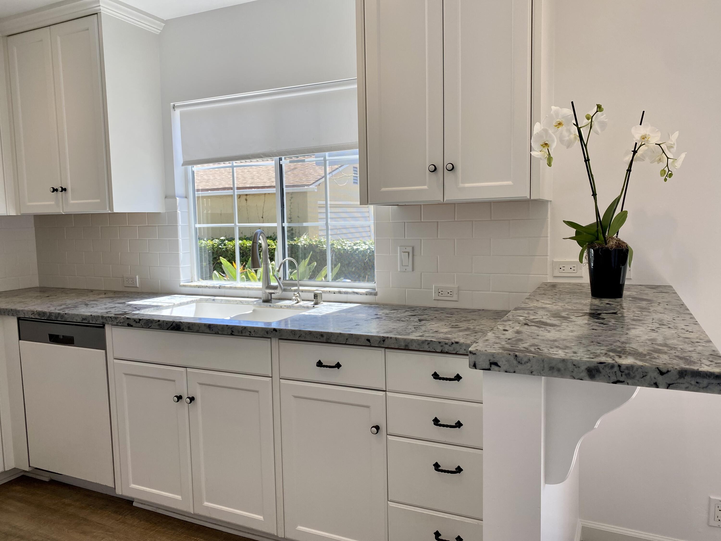 4854 8th Street Carpinteria, CA 93013 - Photo 16 of 22 a kitchen with granite countertop white cabinets and white stainless steel appliances with a window