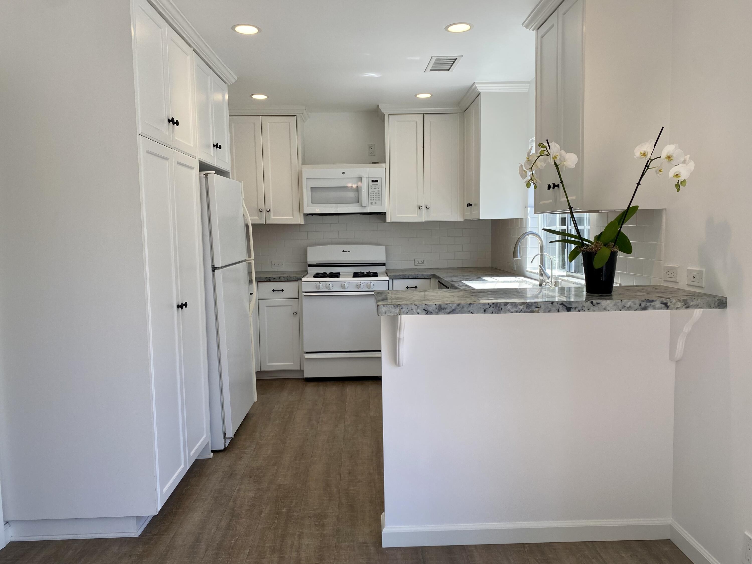 4854 8th Street Carpinteria, CA 93013 - Photo 8 of 22 a kitchen with stainless steel appliances granite countertop a refrigerator sink and white cabinets