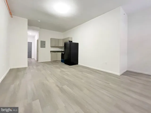 a view of a refrigerator in kitchen and an empty room