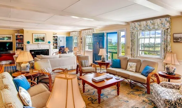 a living room with furniture a fireplace and large windows