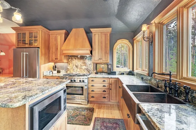 a large kitchen with stainless steel appliances granite countertop a stove a sink and a refrigerator