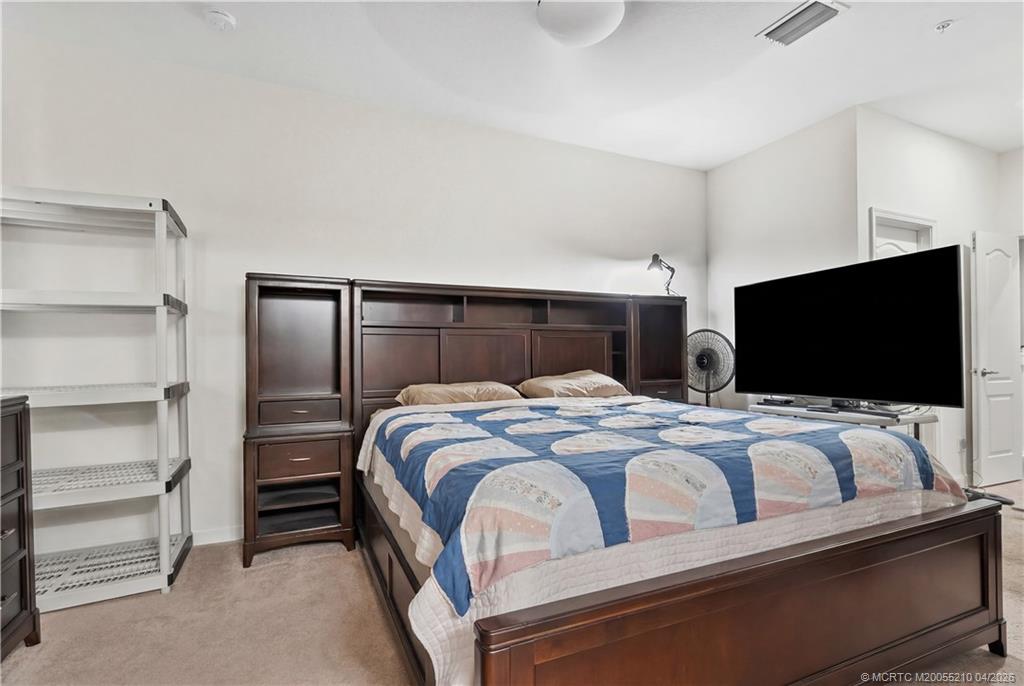 9456 Southwest Merlin Court Stuart, FL 34997 - Photo 14 of 23 a bedroom with a bed and a flat screen tv