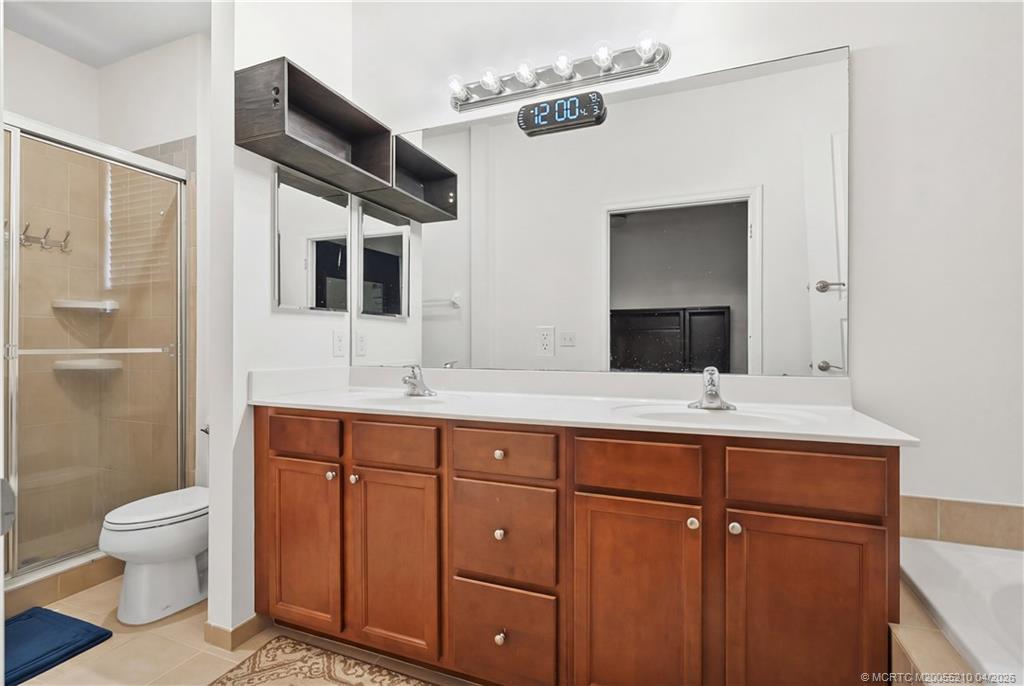 9456 Southwest Merlin Court Stuart, FL 34997 - Photo 16 of 23 a bathroom with a double vanity sink and mirror