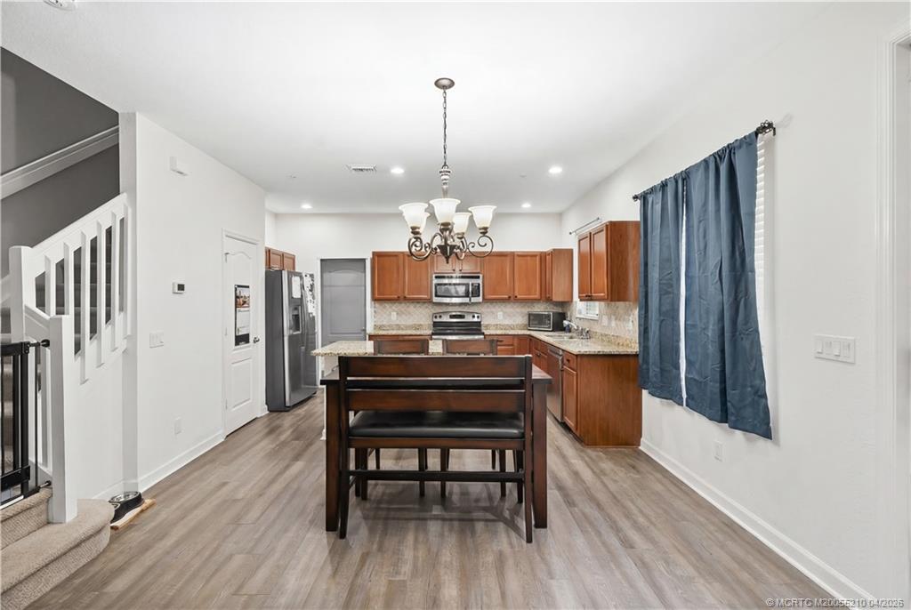 9456 Southwest Merlin Court Stuart, FL 34997 - Photo 8 of 23 a kitchen with refrigerator dining table and chairs