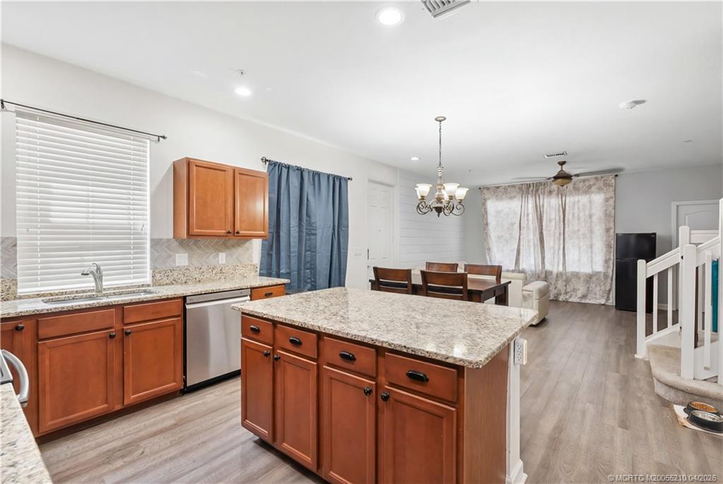 9456 Southwest Merlin Court Stuart, FL 34997 - Photo 10 of 23 a kitchen with granite countertop a sink stove and cabinets