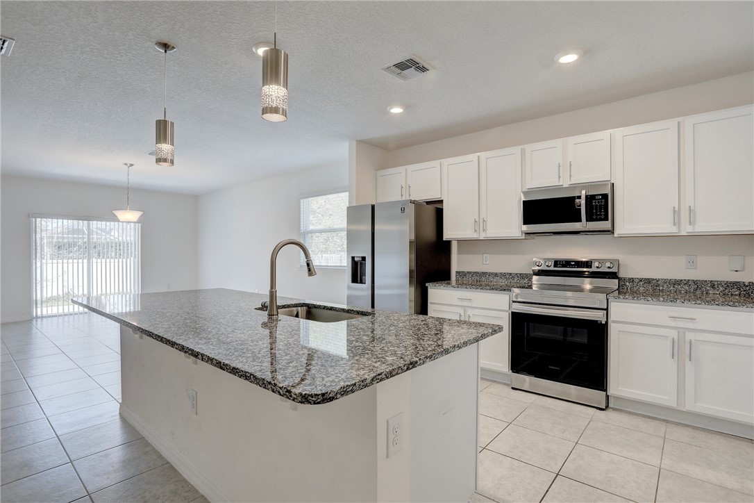 406 Easy Street Sebastian, FL 32958 - Photo 18 of 36 a kitchen with granite countertop a sink stainless steel appliances and white cabinets