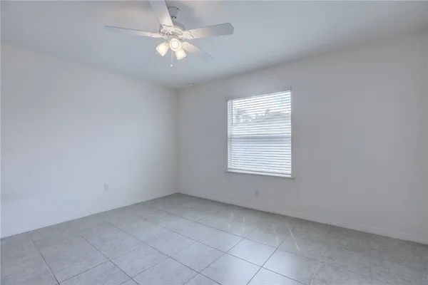 a view of an empty room with window chandelier fan