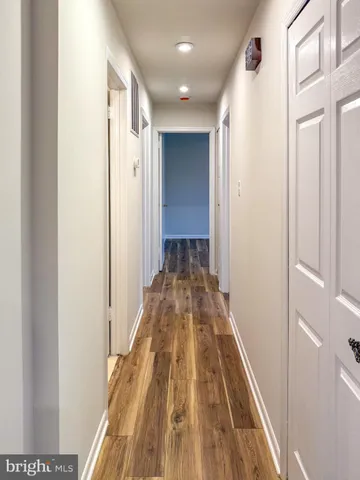 a view of a hallway with wooden floor and a bathroom