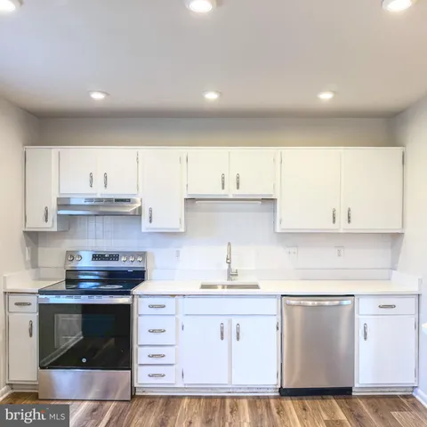 a kitchen with granite countertop a stove top oven sink and cabinets