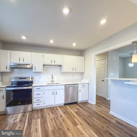 a large kitchen with stainless steel appliances kitchen island granite countertop a refrigerator and a sink