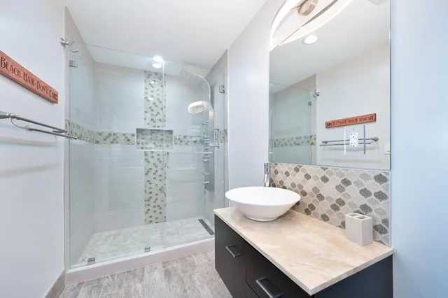 a bathroom with a granite countertop sink a toilet a mirror and shower