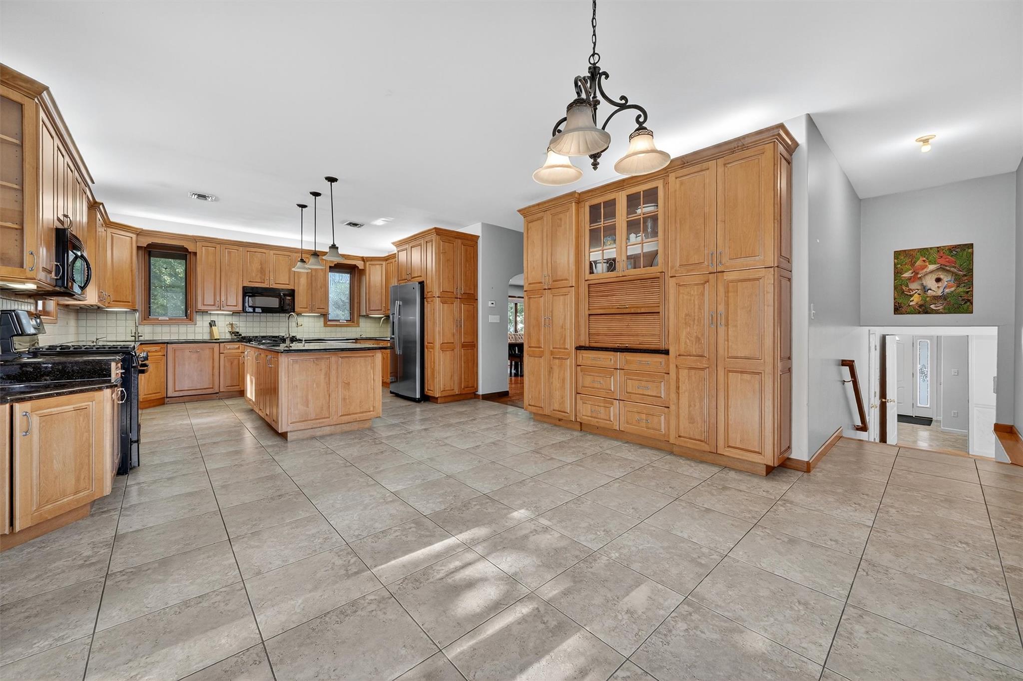 15 Dr Frank Road Spring Valley, NY 10977 - Photo 13 of 50 Kitchen featuring black appliances, tasteful backsplash, a kitchen island, glass insert cabinets, and pendant lighting