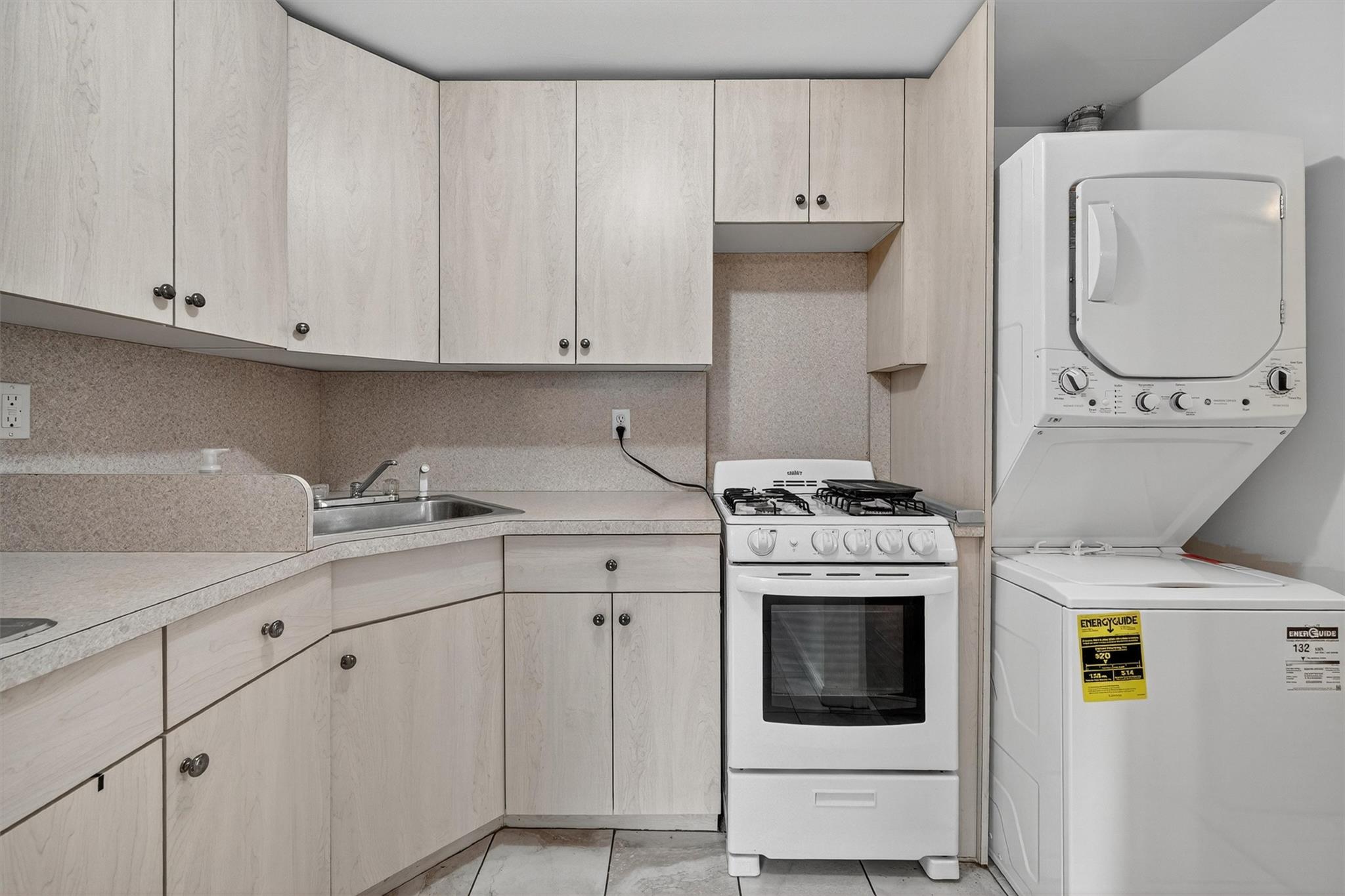 15 Dr Frank Road Spring Valley, NY 10977 - Photo 37 of 50 Kitchen featuring white range with gas cooktop, stacked washing machine and dryer, light countertops, and light brown cabinets